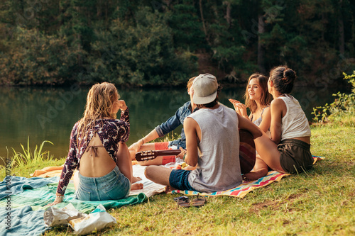 Young people having picnic near a lake