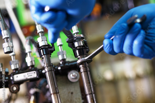 Professional mechanic testing diesel injector in his workshop.