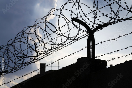 Dramatic clouds behind barbed wire fence on a prison wall