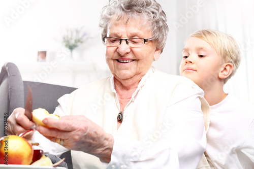  Babcia opiekuje się dzieckiem. Babcia obiera dla wnuczka jabłko ze skórki 