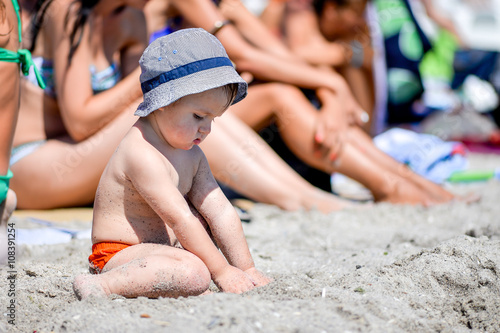 Little boy sitting on the sand at the beach