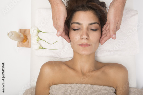 Massaggio al viso a bellissima donna distesa su un lettino di un centro benessere.