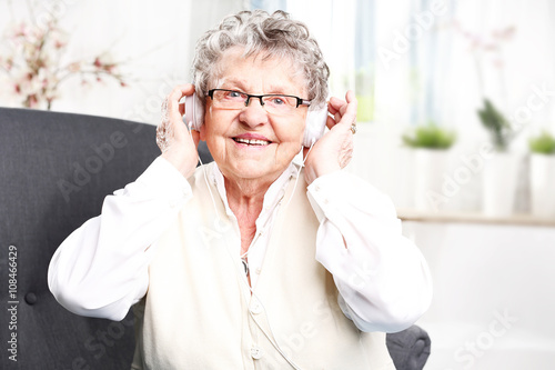 Babcia słucha muzyki. Starsza kobieta z słuchawkami na uszach słucha muzyki