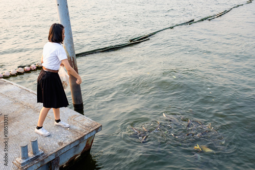 woman student feeding fish at port