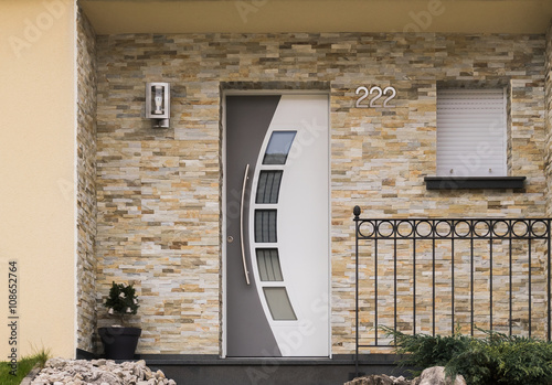 Moderner Eingang eines Hauses mit Haustür Fenster Geländer und Verblender aus Sandstein