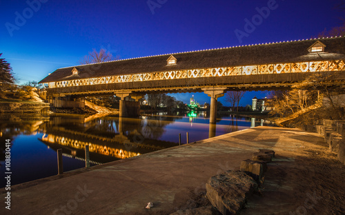 Frankenmuth Covered Bridge At Night. Frankenmuth wooden bridge illuminated at night with the city skyline in the background. Frankenmuth, Michigan.