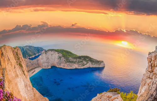 Navagio beach with shipwreck and flowers against sunset on Zakyn