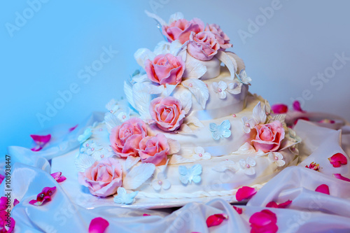 White multi level wedding cake with pink roses flower decorations