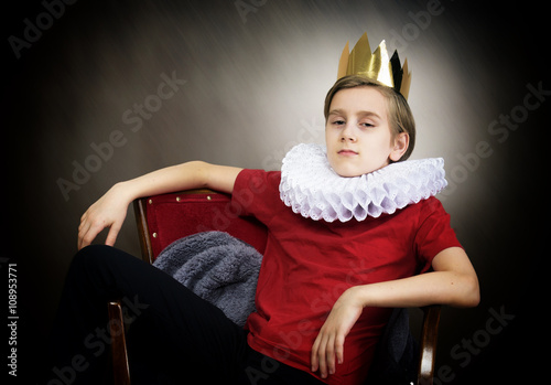 Crowned boy sitting in an armchair