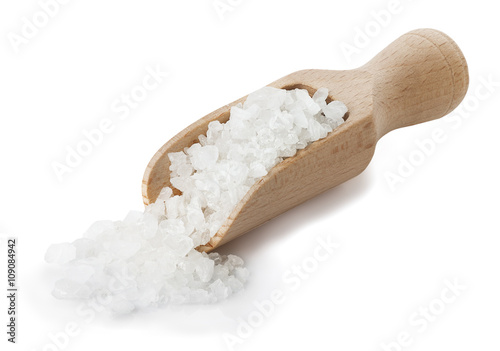 Sea salt poured from wooden scoop