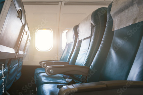 Interior of airplane with empty seats and sunlight at the window. Travel concept
