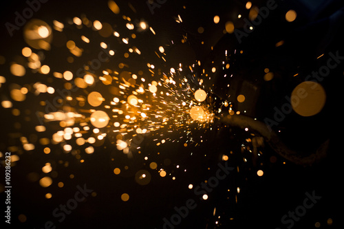 Glowing flow of steel metal spark dust particles and bokeh shine in the dark background 