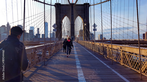 People walking on the Brooklyn Bridge towards Manhattan in the evening, New York.