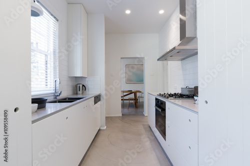 Renovated white galley style kitchen in modern apartment