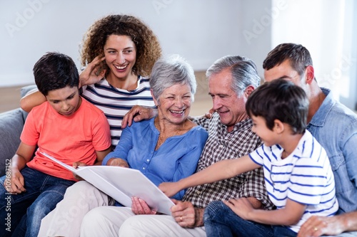 Happy family sitting on sofa and looking at photo album