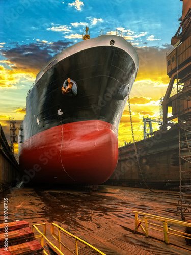 Big ship during repairs on dry dock in shipyard.