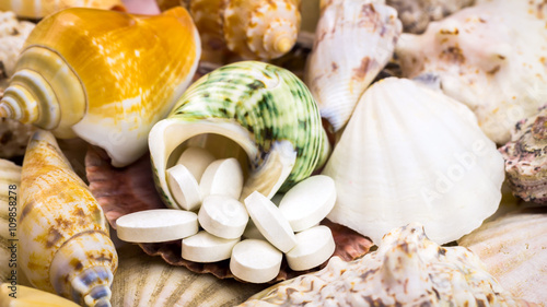Calcium natural food supplement pills on the beautiful seashells background