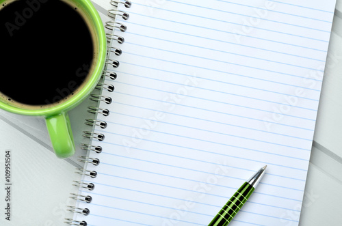 Empty notebook with cup of coffee on table