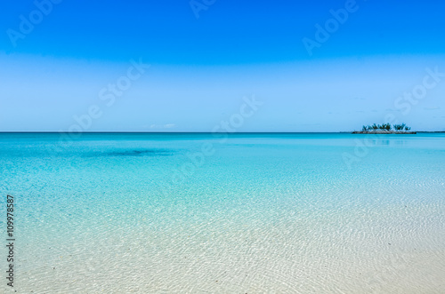 Turquoise, crystal clear water and a small island in the background on Eleuthera (Bahamas).