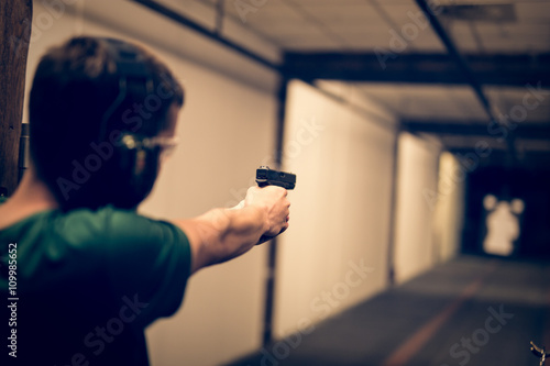 Man aiming pistol at target in indoor firing range or shooting range