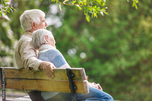 Elderly couple resting on a bench in the park