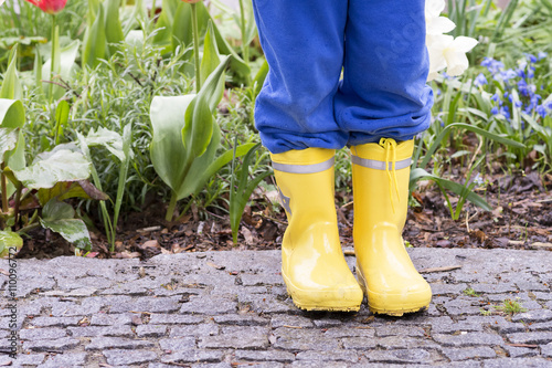 Child in yellow wellington boots in garden