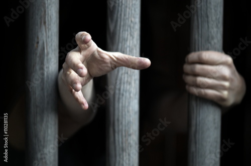 prisoner behind wooden bars begging for help