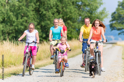 Familie fährt Fahrrad auf Feldweg, Mutter, Vater und Kinder gemeinsam