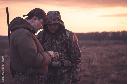 Hunters spot their position via smartphone in rual field during hunting season 