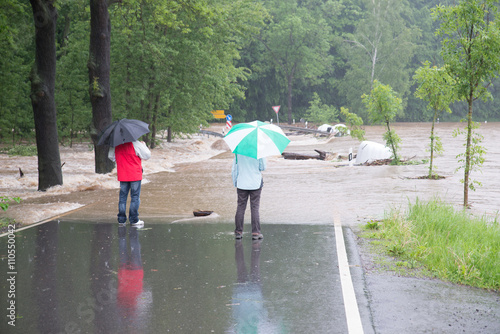 Klimawandel ? Hochwasser 2013 - 2 Passanten stehen auf der überfluteten Straße bei Regen und Hochwasser