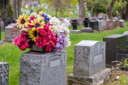 Flowers on a tombstone in a cemetary with headstones in the background