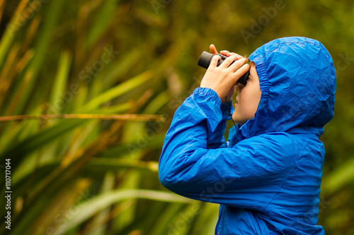 young boy bird watching in a forest