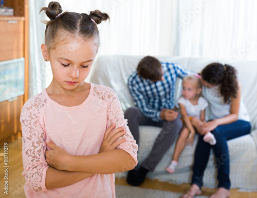 girl sad because of jealous younger sister to parents