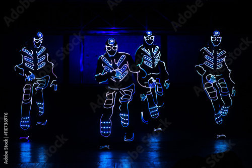 dancers in led suits on dark background, colored show