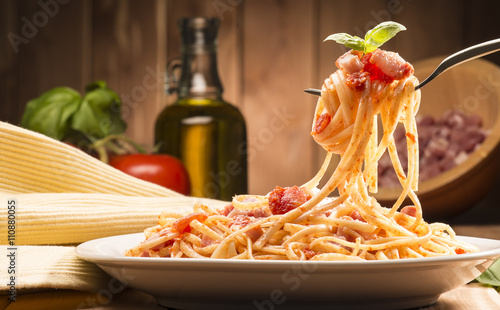 spaghetti with amatriciana sauce in the dish on the wooden table