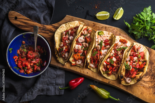 Shrimp tacos with homemade salsa, limes and parsley 