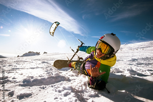 Happy snowboarder with kite lies in snowdrift. Sheregesh resort, Siberia, Russia