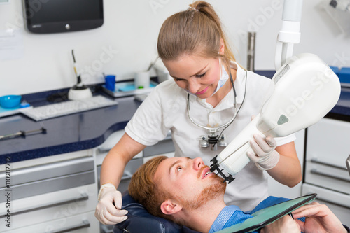 dentist examining the teeth of a patient using x-ray apparatus