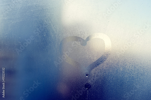 Love heart drawing on glass. The window is fogged up with drops