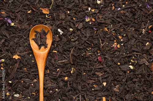 black tea leaves with flowers and fruits with wooden spoon