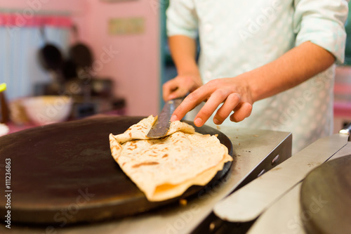 Young man cooking crepes with chocolate in a food truck.