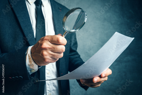 Tax inspector investigating financial documents through magnifying glass