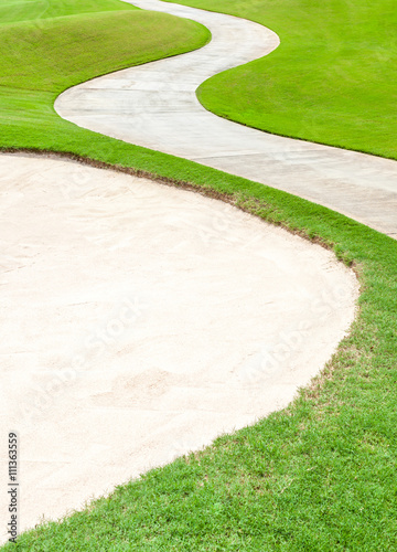 The curved pathway and sand bunker in beautiful green golf cours