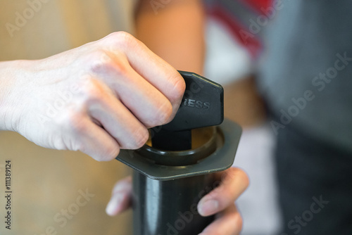 Step by step aero press coffee preparation Bearded barista in blue jeans shirt press aeropress to fill glass with beverage Professional coffee brewing cafe shop