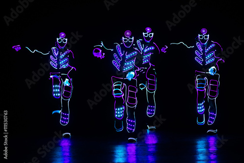 dancers in led suits on dark background, colored show