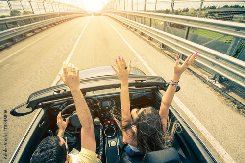 Happy couple driving on the road into the sunset in a sports car