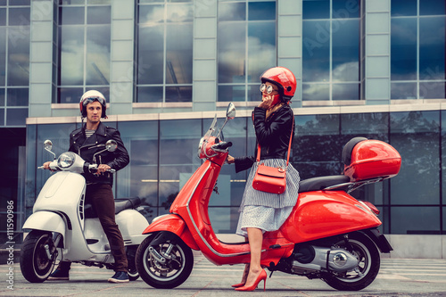 Male and female having fun on moto scooters.