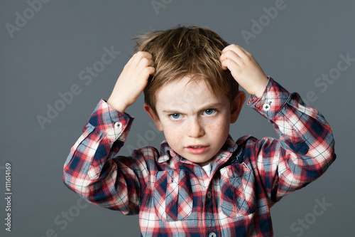 young boy with freckles scratching his hair for head lice