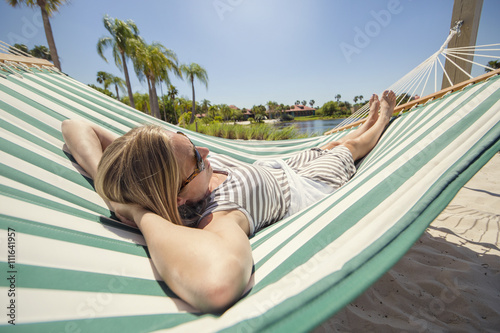 Woman sunbathing, relaxing and resting in a hammock while staying at a tropical resort on vacation