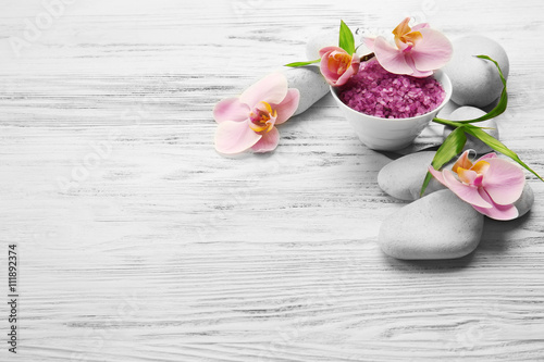 Spa stones, sea salt and orchid flowers on wooden background